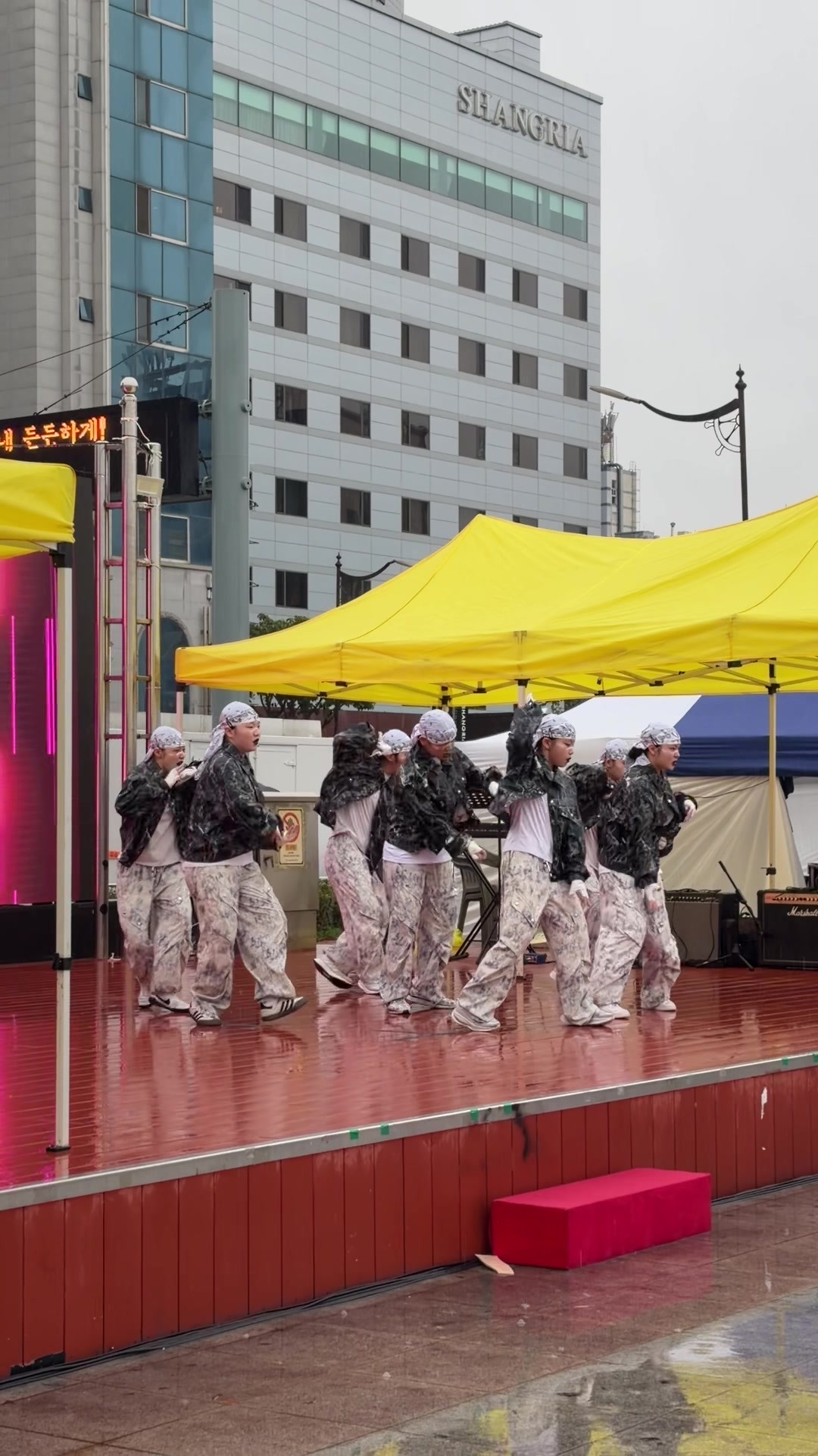 Excited dance crew performing in black jackets and camo pants.